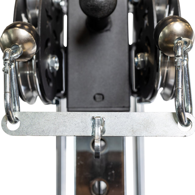 Close-up of the Bells of Steel 2 to 1 Cable Attachment Adapter with two carabiners on a horizontal metal bar, part of fitness equipment.