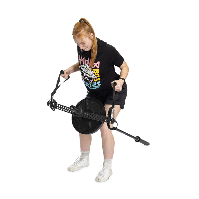A person with red hair in a ponytail uses the Bells of Steel 30 D-Handle Bar Cable Attachment with Carabiners, wearing a black T-shirt, black shorts, and white sneakers, standing on a white background.