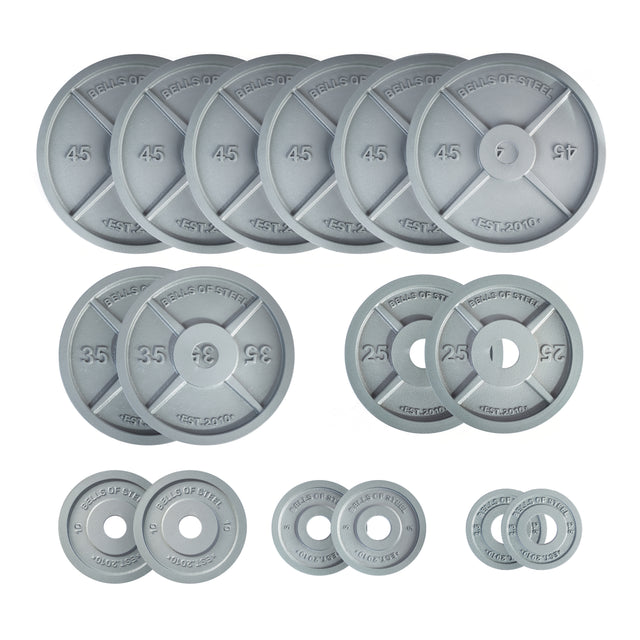 The Bells of Steel Machined Iron Olympic Weight Plate Sets in silver, with precision hole fit and labeled weights, are neatly arranged by size on a white background.