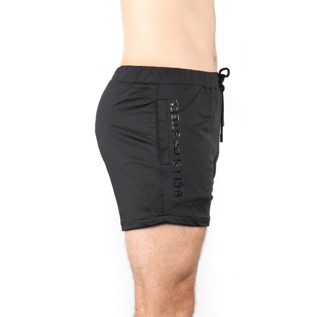 A person in Bells of Steel Gym Shorts with the brand name printed vertically on the side, shown from the side against a white background.