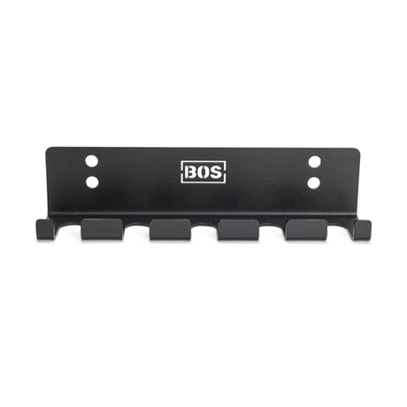 The Bells of Steel Hanging Barbell Holders is a black metal wall rack with six hooks, four screw holes for secure mounting, and a white BOS logo at the center—perfect for organizing your lifting space in style.