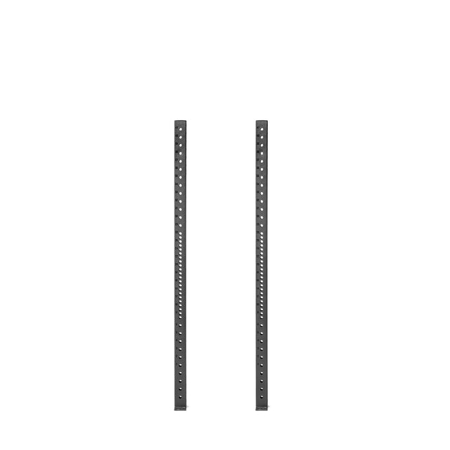 Two tall, black Hydra Vertical Uprights by Bells of Steel stand parallel against a white background, featuring evenly spaced holes for adjustable rack attachments.