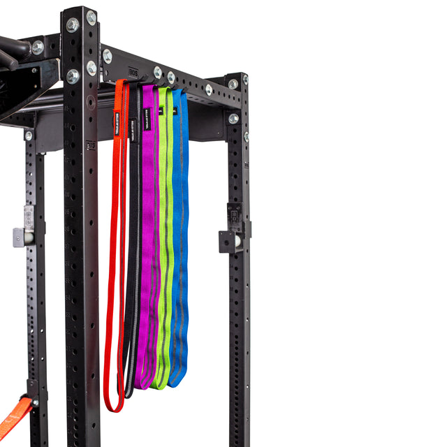 A set of colorful resistance bands hangs from a Bells of Steel Accessory Holder (Wall or Hydra Mounted) attached to a black metal power rack, highlighting practical storage for your gym accessories.