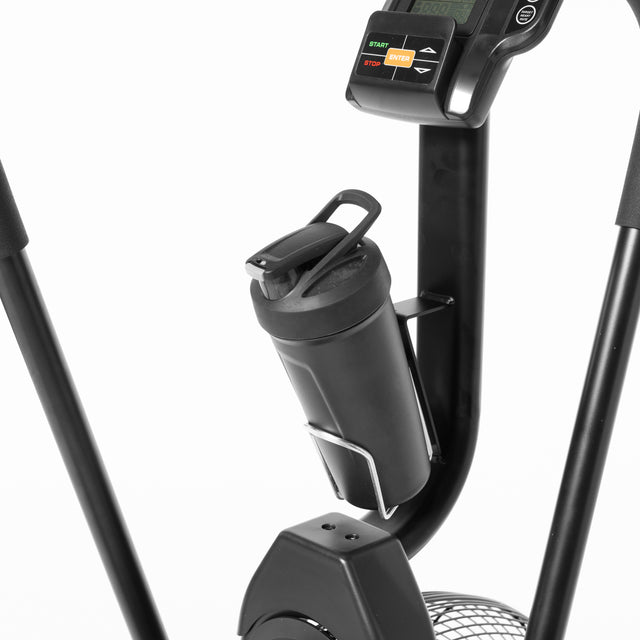 Close-up of the Bells of Steel Residential Air Bike with Wind Guard's black handlebar area, showcasing an attached water bottle holder with a black water bottle, a digital display for tracking workouts, and visible start/stop buttons—ideal for a full-body workout in your home gym.