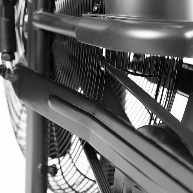 Close-up of a large industrial fan with visible metal blades and a protective grille in black and white, similar to the sturdy design of the Bells of Steel Residential Air Bike with Wind Guard, perfect for a full-body workout.