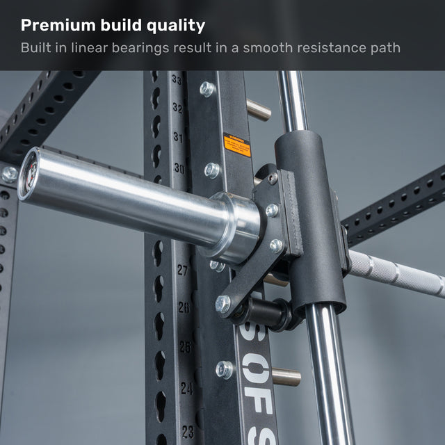 Close-up of a gym machine’s barbell and frame, showing Anvil Handles by Bells of Steel USA with linear bearings and resistance system. Text at top: “Premium build quality. Built-in linear bearings for smooth resistance.”.