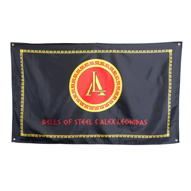 A black flag displays a red and gold emblem with a stylized "A," bordered by a Greek key, above "Bells of Steel & Alex Leonidas" in bold red—celebrating the Bells of Steel Alex Leonidas Onyx Bar and its signature Cerakote finish.