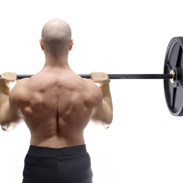 A muscular, bald person seen from behind lifts a Bells of Steel Alex Leonidas Onyx Bar with a sleek Cerakote finish across their upper back, wearing black shorts, set against a white background.