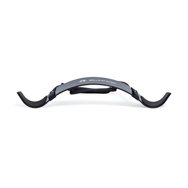 The Bells of Steel Arm Blaster is a curved black arm support with padded ends and an adjustable strap, designed for bicep curls and proper form, featuring the Bells of Steel logo on the front.
