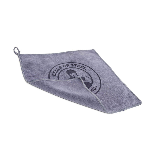 The Bells of Steel Barbell Cleaning Microfiber Towel is a lint-free gray towel with stitched edges, a hanging loop, and features the Bells of Steel logo plus a person lifting a kettlebell—ideal for cleaning barbells.
