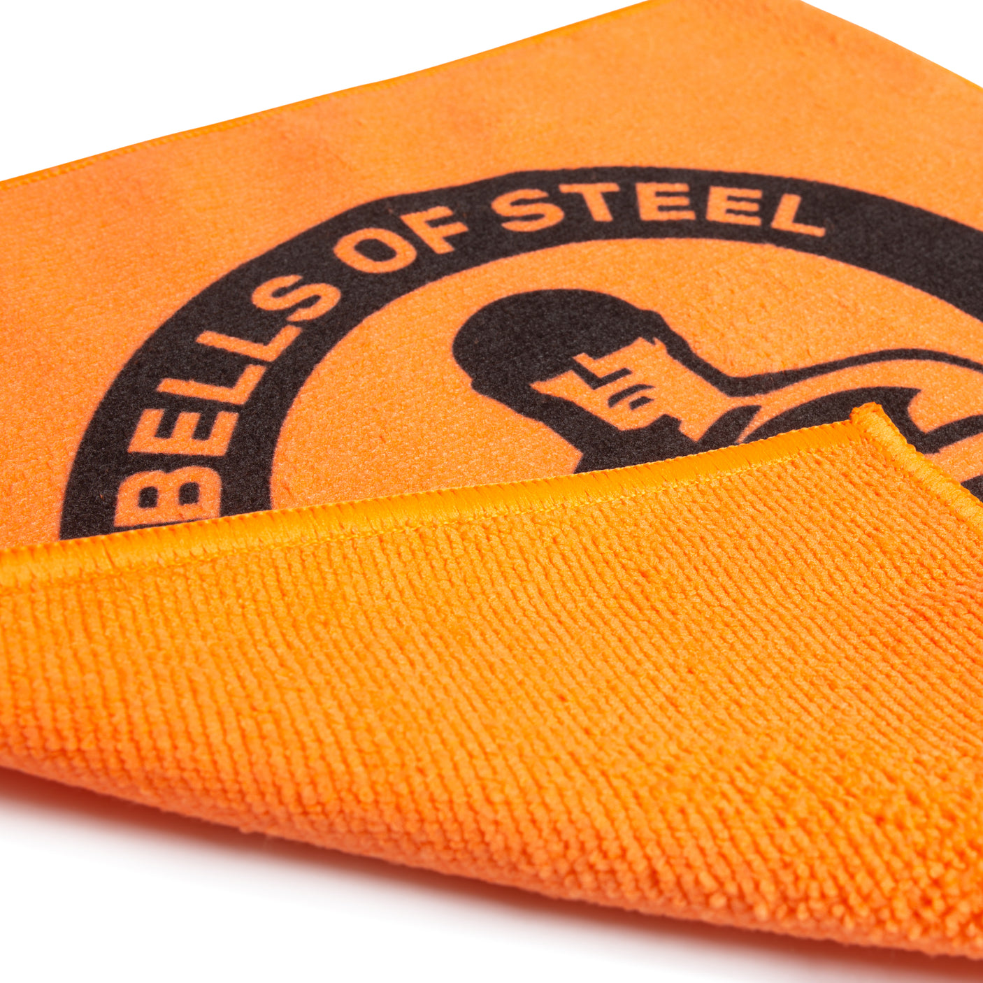 The Bells of Steel Barbell Cleaning Microfiber Cloth is an orange towel with a black logo and stylized figure, partially folded to reveal its textured underside—ideal as a lint-free cleaning cloth for barbells.