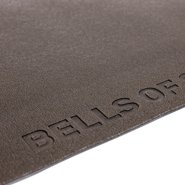 Close-up of a textured brown Bells of Steel Cardio Machine Floor Mat surface, with the embossed "BELLS OF" logo partially visible in the lower right corner.