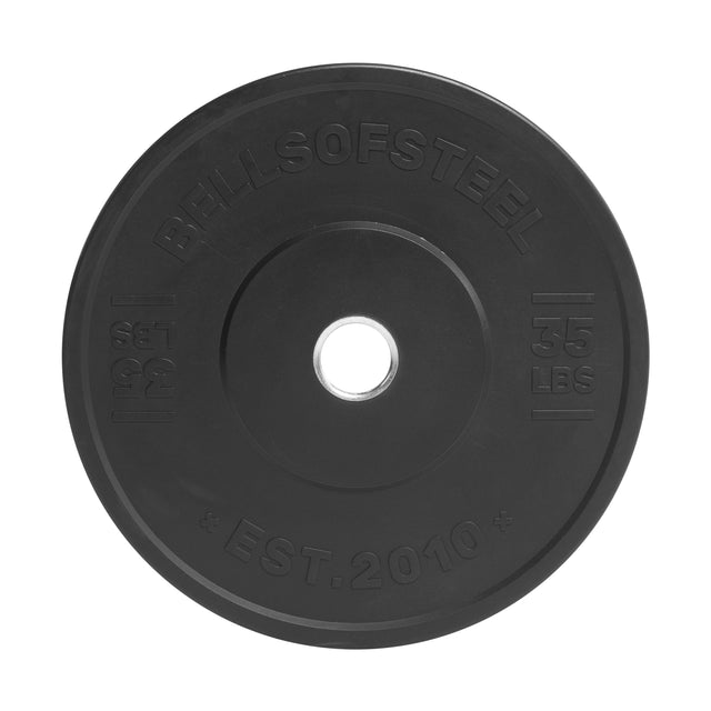 The Bells of Steel All-Black Bumper Plate features medium bounce rubber, "35 LBS," "15.9 KG," and "EST. 2010" embossed on the surface, plus a stainless steel insert ring for easy barbell mounting.