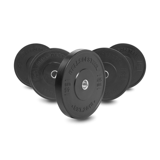 Five Bells of Steel All-Black Bumper Plate Sets with silver centers are arranged in a semi-circle on a white background, each showing clear weight markings and brand name.