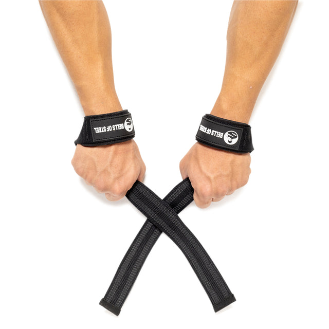 Two hands wearing black Bells of Steel Lifting Straps cross the attached straps in an X shape, highlighting essential grip strength gear against a white background.