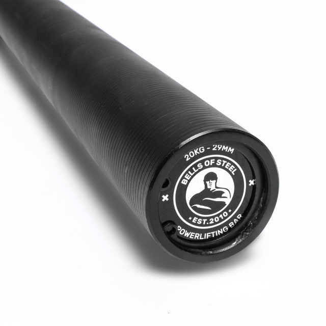 A close-up of a black Bells of Steel Powerlifting Bar with “20KG - 29MM Powerlifting Bar” and logo on the end cap, highlighting this top budget barbell against a white background.