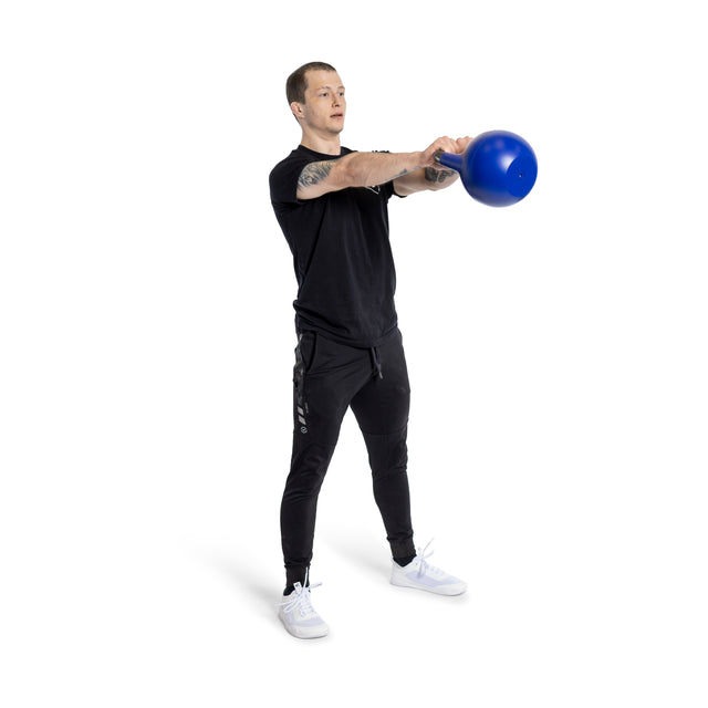 A man in black workout gear demonstrates his kettlebell technique using the Bells of Steel Adjustable Competition Kettlebell. He swings it forward with both hands while standing on a white background, wearing white sneakers.