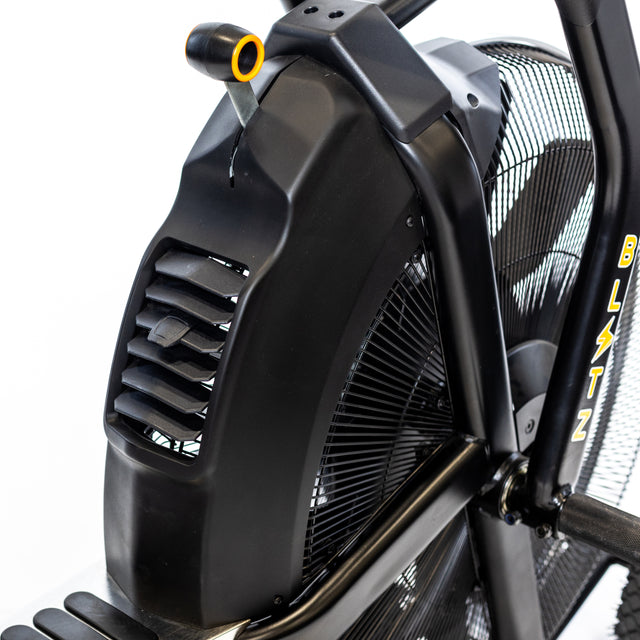 Close-up of the Bells of Steel Blitz Max Air Bike, featuring a sturdy frame, large fan with protective cover, and bold yellow "BLITZ" branding—designed for commercial gym use.