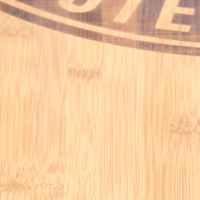 Close-up of a light wooden surface showcasing the "Deadlift Platform Bamboo Insert (Right)" by Bells of Steel. The partial view includes a circular logo's bottom curve, some indistinct text, and visible wood grain, enhanced by the bamboo insert that adds an organic touch.