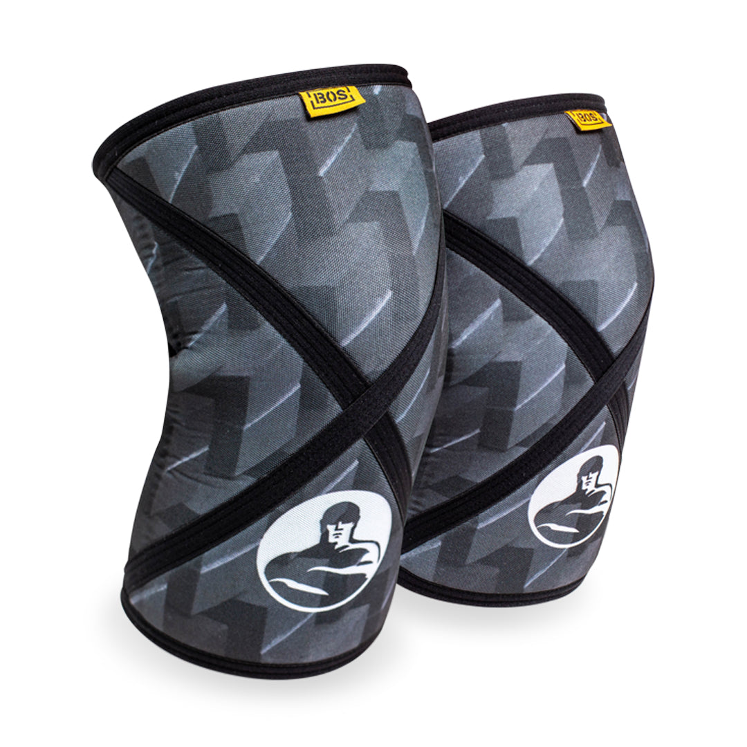 Bells of Steel Knee Sleeves in black and gray feature a muscular figure logo and yellow label, offering a contoured design for effective squat support.