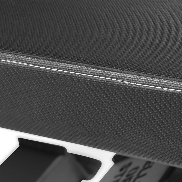 A close-up shows the textured black fabric with white stitching of the Buzz-Saw Heavy-Duty Adjustable Bench by Bells of Steel, partially revealing its black metal structure.