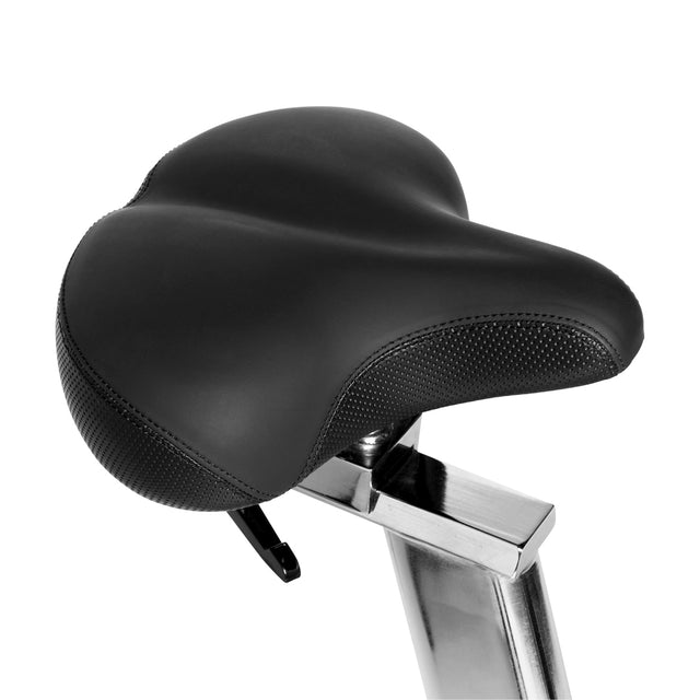 A close-up of the Blitz Air Bike seat by Bells of Steel, featuring a wide, cushioned black design on a silver seat post against a white background—ideal for your home gym.