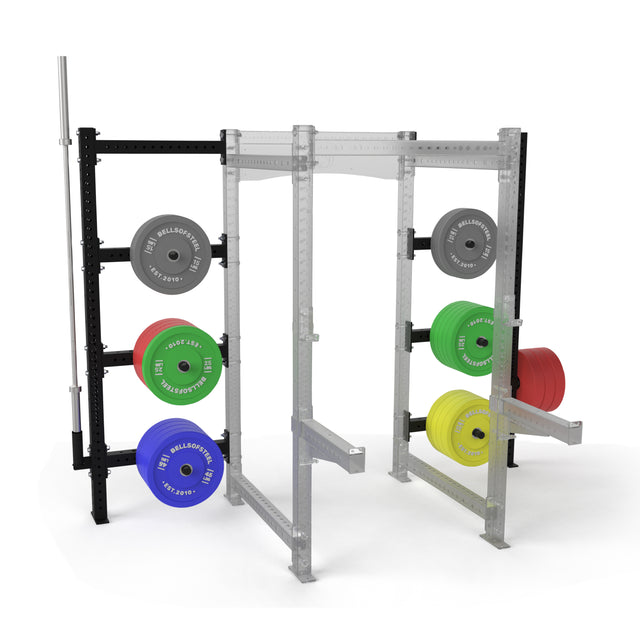 The Bells of Steel Hydra Batwing Storage is a modular gym rack with a partially transparent frame, featuring gray, blue, green, yellow, and red weight plates on power rack pegs and a barbell mounted on the left side.