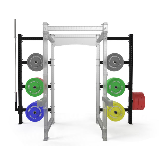 The Bells of Steel Hydra Batwing Storage is a modular gym rack designed for efficient strength training, with a power rack, barbell, and colorful weight plates (gray, green, blue, yellow, red) neatly stored on both sides.