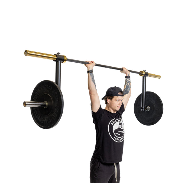 A person lifts a barbell with Bells of Steel Camber Bar Attachments (Pair) and side handles overhead, engaging stabilizer muscles, while wearing a black cap and logo T-shirt against a white background.