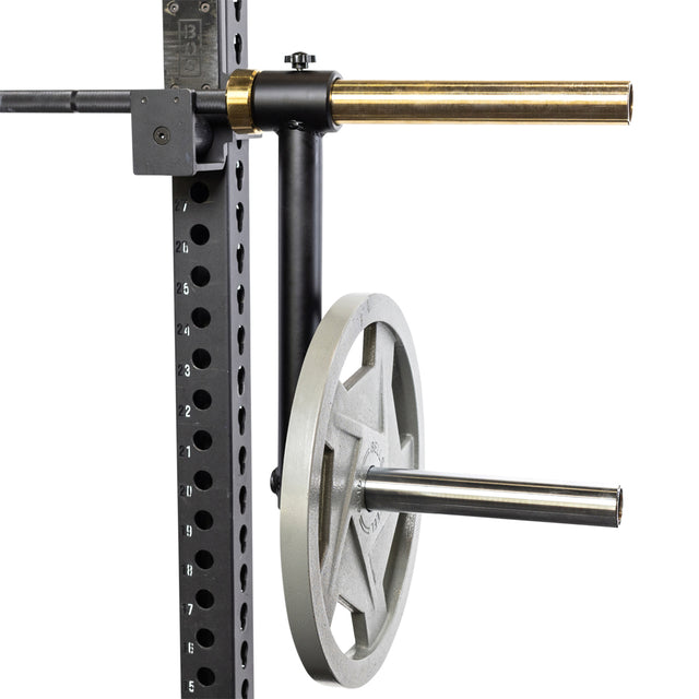 The Bells of Steel Camber Bar Attachment - Pair, mounted horizontally on a squat rack designed for Olympic barbells, uses evenly spaced holes to securely hold weight plates for easy storage.