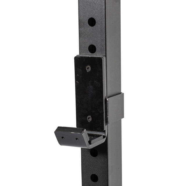 A close-up of a Bells of Steel Cable Crossover (2.3" x 2.3" Racks) attachment in black metal, mounted on a perforated vertical post, commonly used for supporting barbells on squat or power racks in gyms.