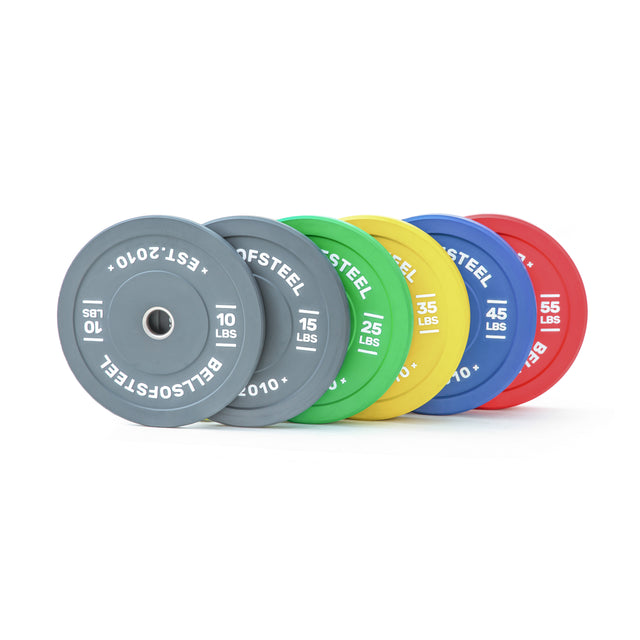 Six Bells of Steel Colored Bumper Plate Sets—10, 15, 25, 35, 45, and 55 lbs—feature gray, green, yellow, blue, and red plates with stainless steel inserts and precise weight markings.