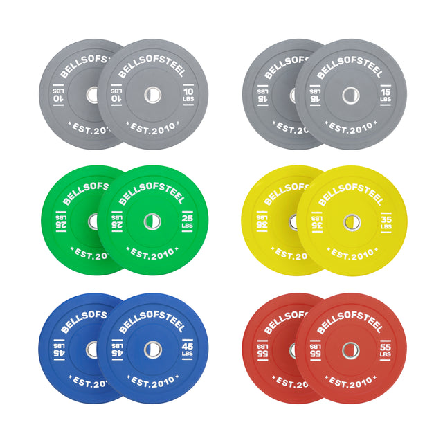 The Bells of Steel Colored Bumper Plate Sets include six pairs in gray, green, yellow, blue, and red, each with accurate pound labels and a stainless steel insert. Plates are arranged in two rows of three pairs.