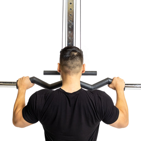 A short-haired individual in a gym wears a black shirt, using the Bells of Steel Fat Bar - Olympic Curl Bar Cable Attachment to lift weights, enhancing their grip strength while facing away from the camera.