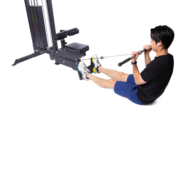 A person uses the Bells of Steel Multi Grip Curl Bar Cable Attachment, sitting with legs extended and feet braced to pull the attachment toward their torso for effective arm muscle isolation.