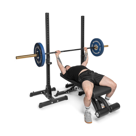 Wearing athletic gear, an individual uses the Bells of Steel Flat / Incline / Decline Weight Bench – Commercial to perform an incline bench press with a barbell in a gym, effectively targeting multiple muscle groups.