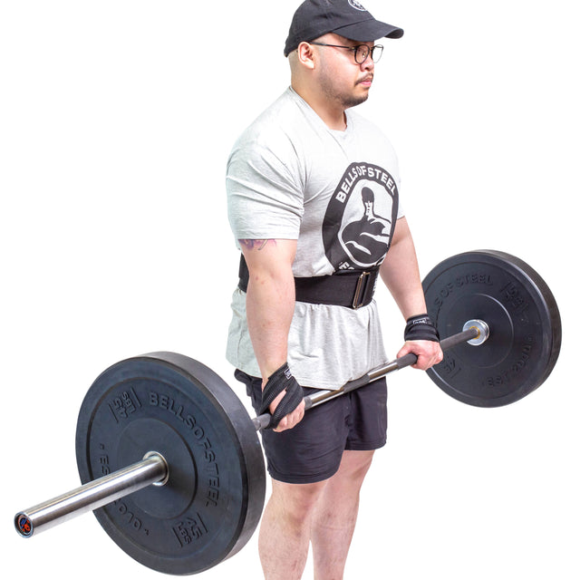 A man lifts weights on a white background using Bells of Steel Classic Figure 8 Lifting Straps to boost grip strength.
