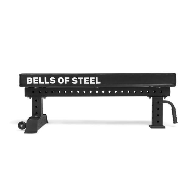 The Bells of Steel Powerlifting Flat Bench is black with white branding, a sturdy metal frame, padded top, handle for easy movement, multiple adjustment holes, and supports up to 1,000 lb.