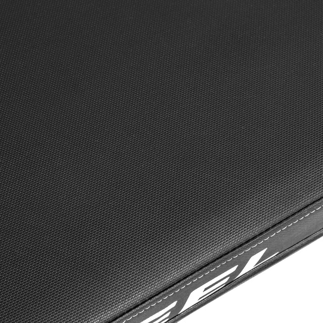 Close-up of the Bells of Steel Powerlifting Flat Bench’s textured black surface, showing white partial text and edge stitching.