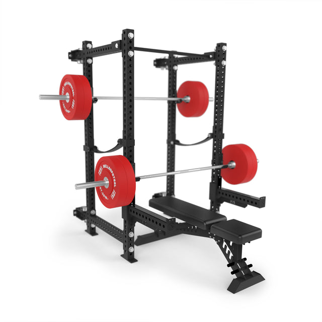 The Bells of Steel Manticore Folding Power Rack (3"x3", 1" holes), with a bench, loaded barbells, and red plates, is set up for squats and bench press—ideal for a home gym—against a white background.