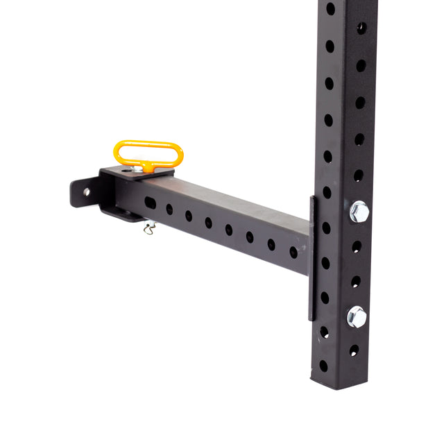 A close-up of the Bells of Steel Folding Rack 2.3" x 2.3" (5/8" Holes) attachment, featuring a yellow handle, adjustable arm, and multiple height holes, secured to a vertical support beam with bolts in a garage gym.