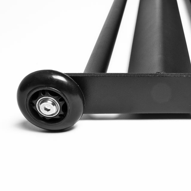 Close-up of a Bells of Steel Glute Ham Slider, a black metal cylinder with a round wheel at one end on a white surface, featuring a central bolt suggesting it's part of an exercise rolling mechanism.