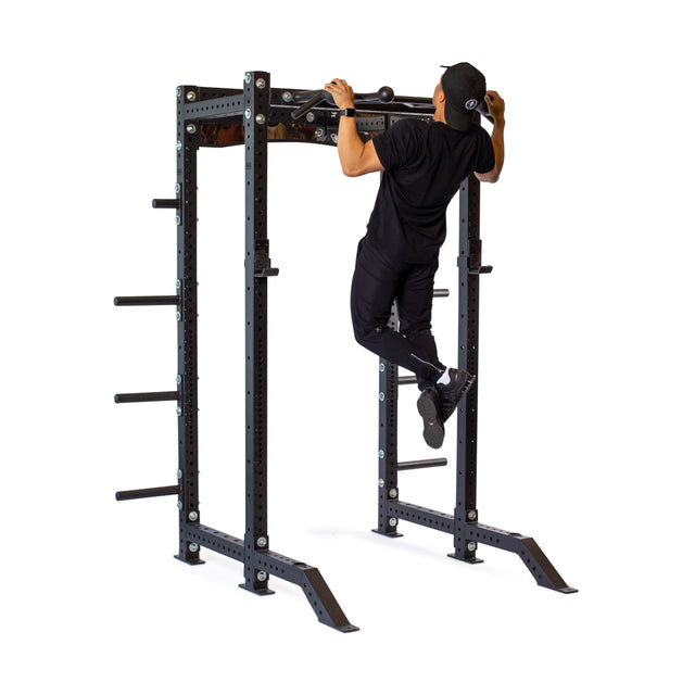 A person in black athletic wear and a cap does a pull-up on the Bells of Steel Globe Pull Up Bar, featuring weight storage pegs for grip strength, against a white background.