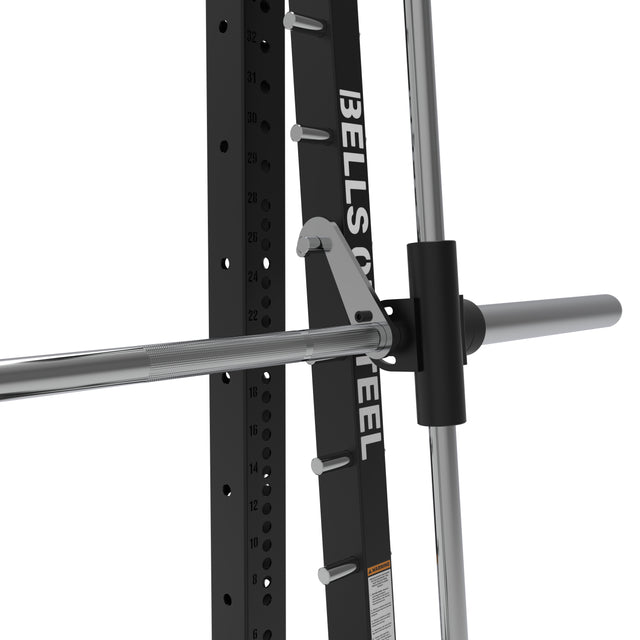 Close-up of the Bells of Steel USA Smith Machine - Hydra (3" x 3", ⅝" Holes), showing a barbell on a vertical metal track with numbered holes and safety catches, with the brand name on the frame.
