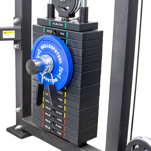 A close-up of a gym weight stack with a Bells of Steel 15 lb plate and the Bells of Steel Weight Stack Pin attached. Weight increments are labeled in pounds and kilograms for easy micro loading on this cable machine.