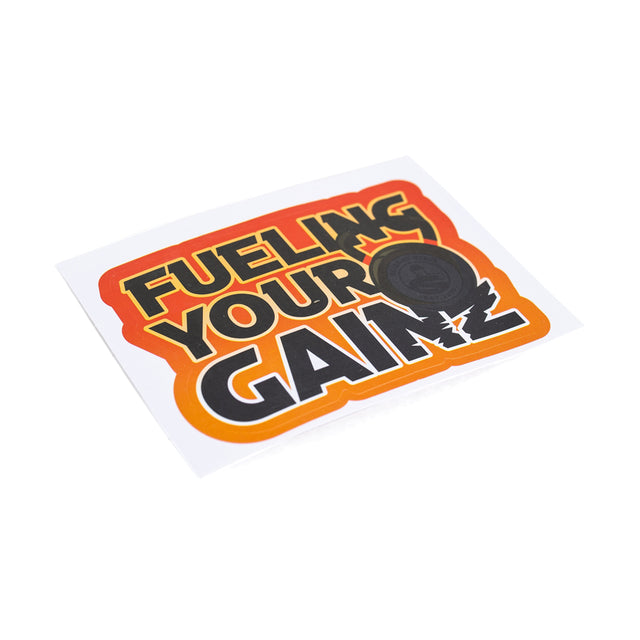 The Bells of Steel Stickers feature "FUELING YOUR GAINS" in bold black and orange on white, with an orange border. "GAINS" includes a weight plate graphic, making these durable vinyl die-cut stickers perfect for your gear.