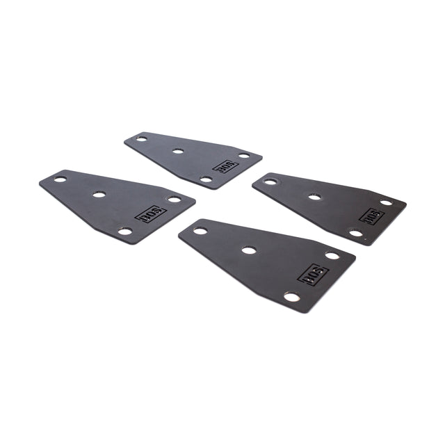 Four black metal mounting brackets with angled edges and three holes each, arranged on a white background. Each bracket, part of the Manticore Flat Foot Components by Bells of Steel, features a small rectangular "VESTA" logo in one corner.