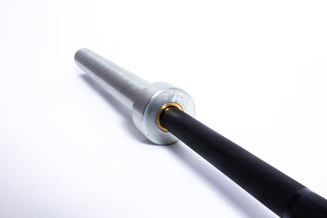 Close-up of the Bells of Steel Multi-Purpose Olympic Barbell on a white background, showcasing its metallic sleeve, brass bushings, and medium-light knurl for optimal grip.