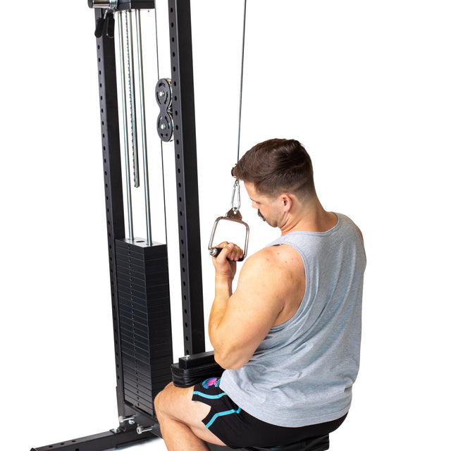 A man in a gray tank top and black shorts is seated on a gym machine, performing a cable pull-down with the Bells of Steel Single D Handle Cable Attachment, gripping the handle with both hands against a white background.