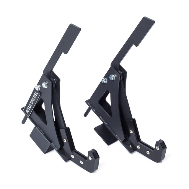 Two black metal Monolift Rack Attachments by Bells of Steel, with triangular cutouts and bolts, stand upright on a white background—ideal for barbell protection and rack compatibility.